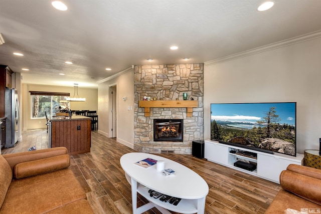 living room featuring crown molding, a stone fireplace, and sink