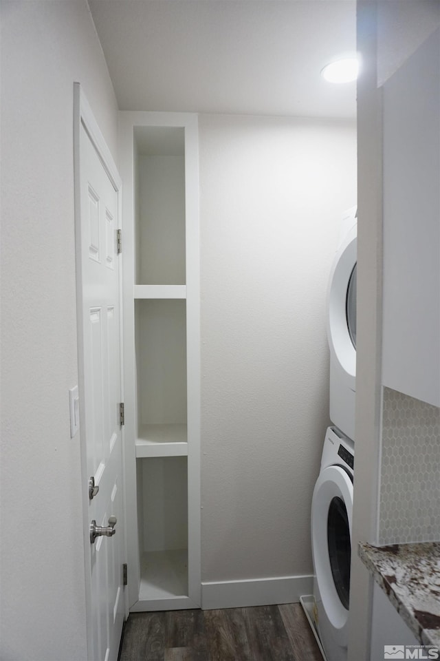 clothes washing area with stacked washing maching and dryer and dark hardwood / wood-style floors