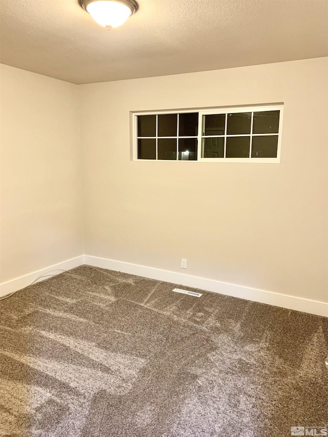 carpeted empty room with a textured ceiling