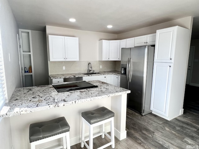 kitchen with sink, stainless steel fridge, a breakfast bar, white cabinetry, and dark hardwood / wood-style floors