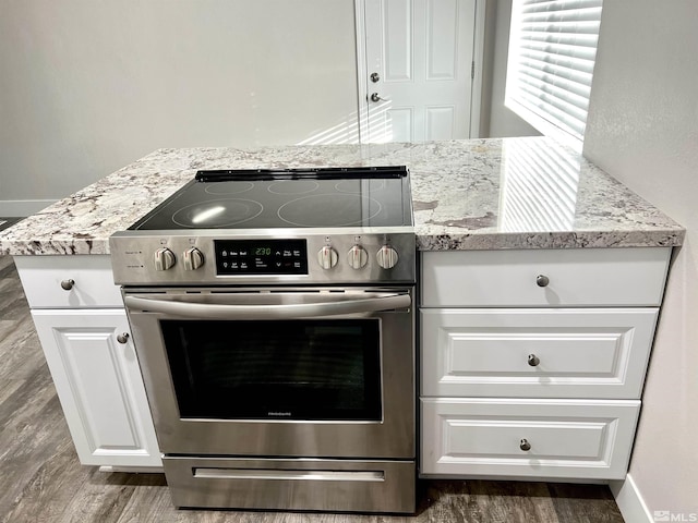 kitchen with white cabinets, light stone countertops, dark hardwood / wood-style floors, and electric range