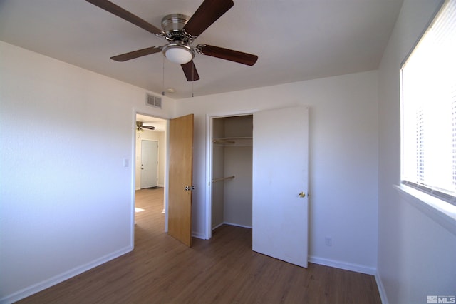 unfurnished bedroom with dark wood-type flooring, ceiling fan, and a closet