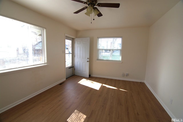 empty room with ceiling fan and dark hardwood / wood-style flooring