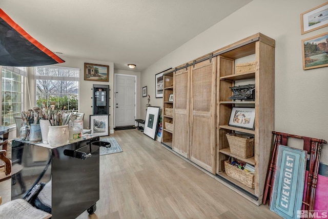 office with light hardwood / wood-style floors and a barn door