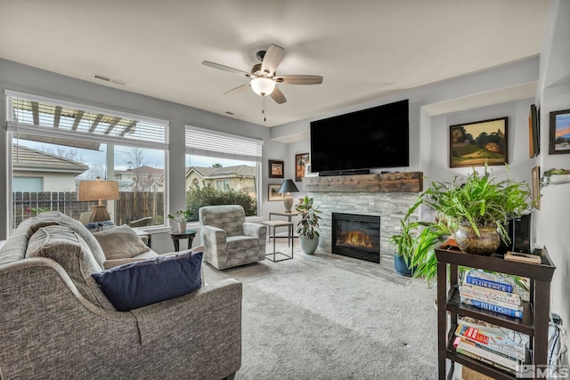 living room with ceiling fan, carpet flooring, and a fireplace