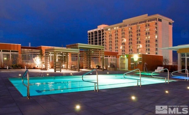 pool at night featuring a patio