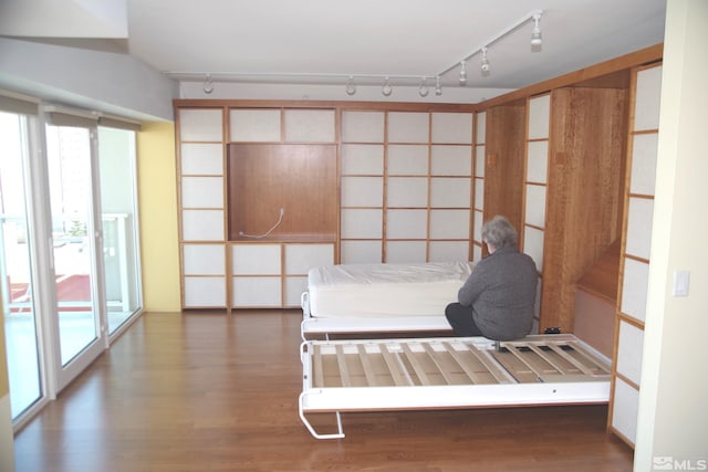 unfurnished bedroom featuring dark hardwood / wood-style floors, access to outside, and track lighting