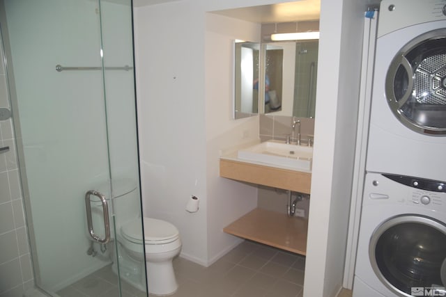 laundry area with tile patterned flooring, stacked washing maching and dryer, and sink