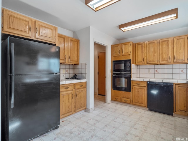 kitchen with tasteful backsplash, tile counters, and black appliances