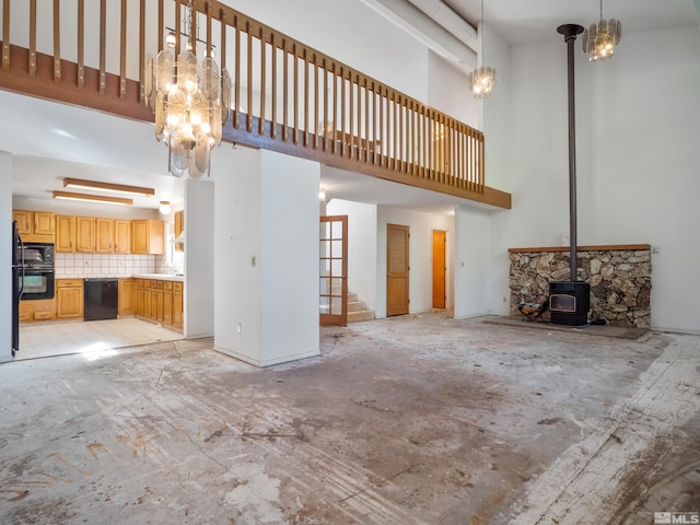 unfurnished living room with a high ceiling and a wood stove