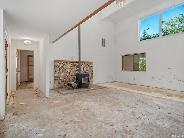 unfurnished living room featuring high vaulted ceiling and a wood stove