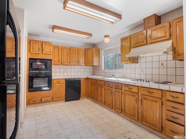 kitchen featuring backsplash, tile countertops, sink, and black appliances