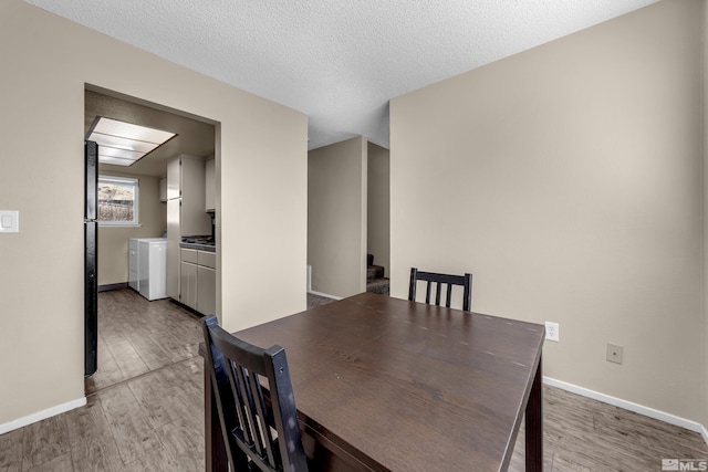 unfurnished dining area with a textured ceiling, independent washer and dryer, and light hardwood / wood-style floors