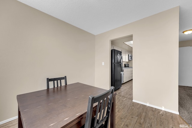 dining room featuring wood-type flooring and a textured ceiling