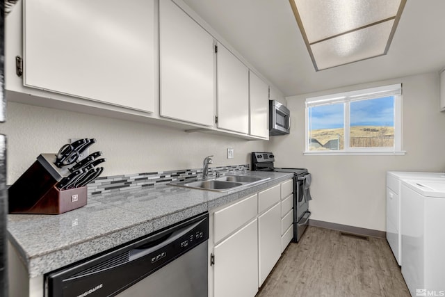 kitchen with white cabinetry, sink, stainless steel appliances, washing machine and dryer, and light wood-type flooring