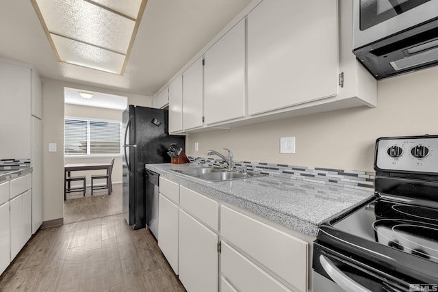 kitchen with sink, light hardwood / wood-style floors, white cabinets, and appliances with stainless steel finishes