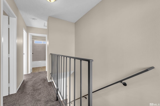 hallway featuring dark colored carpet and a textured ceiling