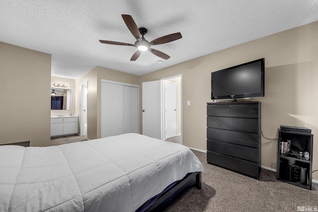 carpeted bedroom featuring ceiling fan, a textured ceiling, ensuite bath, and a closet