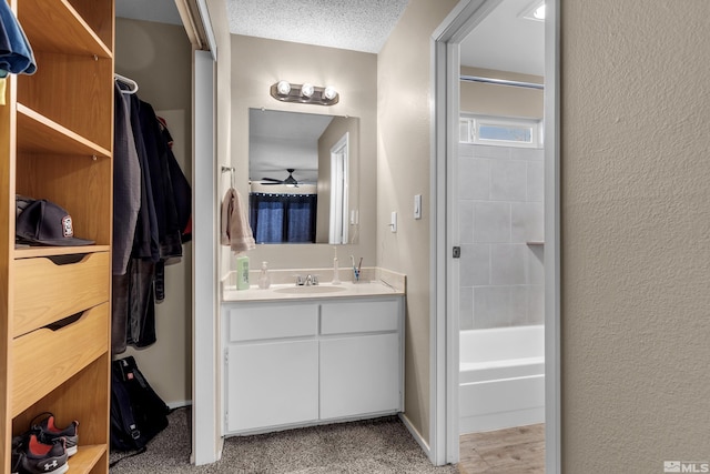 bathroom featuring vanity, ceiling fan, and a textured ceiling