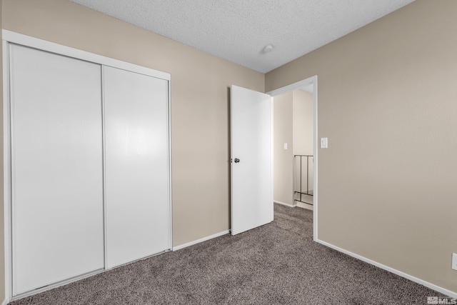 unfurnished bedroom featuring dark carpet, a closet, and a textured ceiling