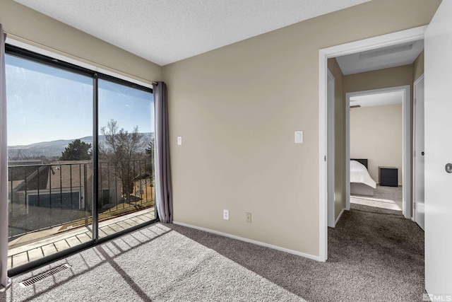 carpeted empty room featuring a mountain view and a textured ceiling