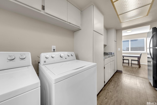 clothes washing area with separate washer and dryer and light wood-type flooring