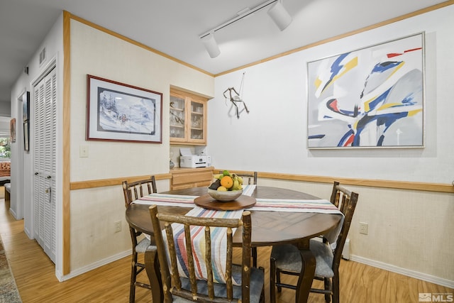 dining room featuring crown molding, light hardwood / wood-style floors, and rail lighting