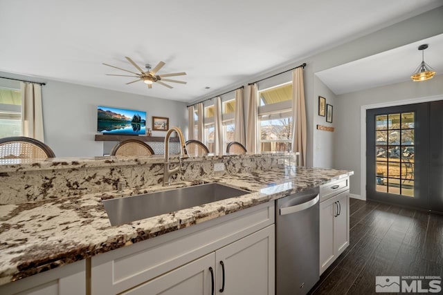 kitchen featuring white cabinetry, dishwasher, sink, hanging light fixtures, and light stone counters