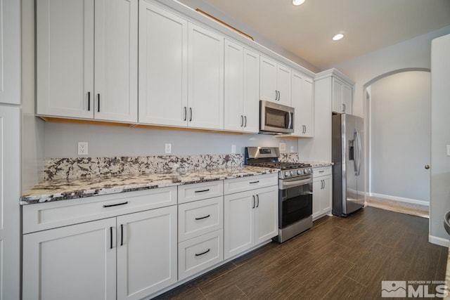 kitchen featuring dark wood-type flooring, stainless steel appliances, light stone counters, and white cabinets