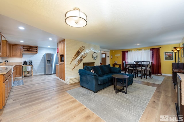 living room with a brick fireplace and light wood-type flooring