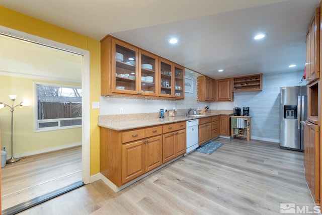 kitchen featuring dishwasher, sink, stainless steel fridge, and light hardwood / wood-style floors