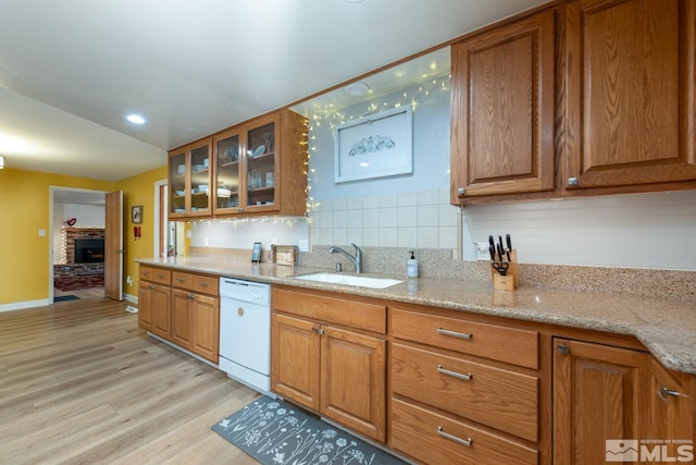 kitchen featuring tasteful backsplash, sink, white dishwasher, light stone countertops, and light hardwood / wood-style flooring