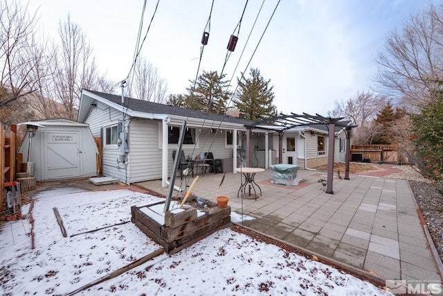 snow covered house featuring a shed, a pergola, and a patio