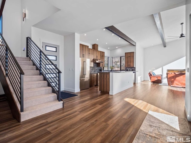 kitchen featuring high end refrigerator, dark hardwood / wood-style flooring, a kitchen island, beamed ceiling, and ceiling fan