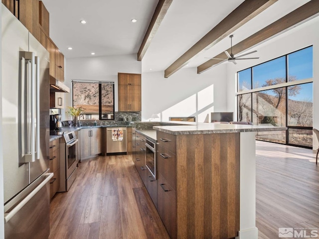 kitchen with dark hardwood / wood-style floors, a kitchen island, beamed ceiling, stainless steel appliances, and decorative backsplash