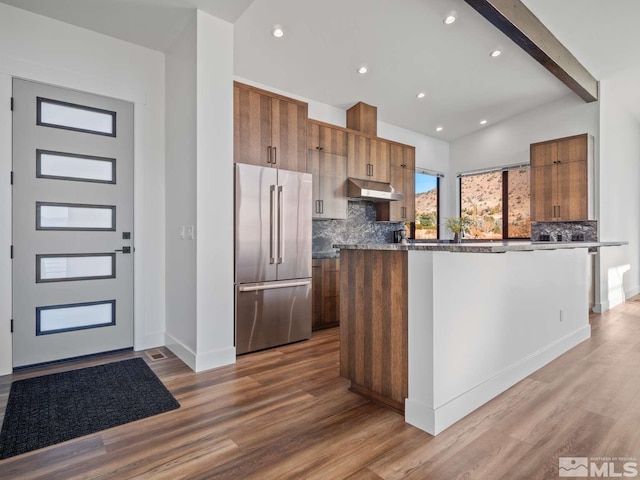 kitchen featuring a center island, high end refrigerator, light hardwood / wood-style floors, and decorative backsplash