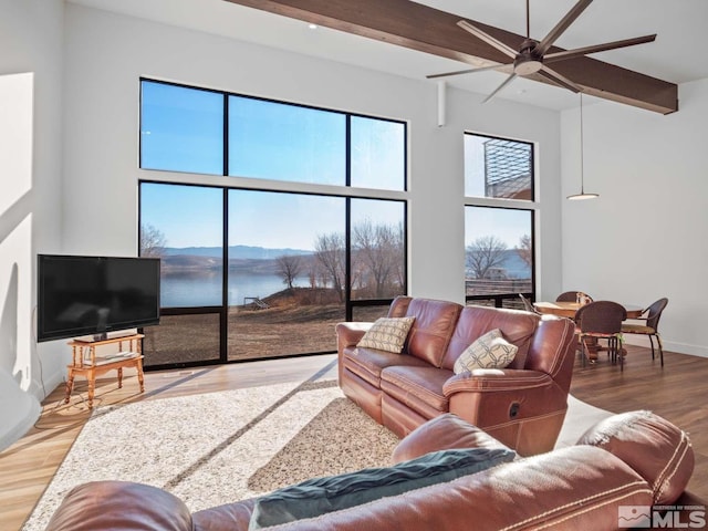 living room with beamed ceiling, hardwood / wood-style flooring, ceiling fan, and a towering ceiling