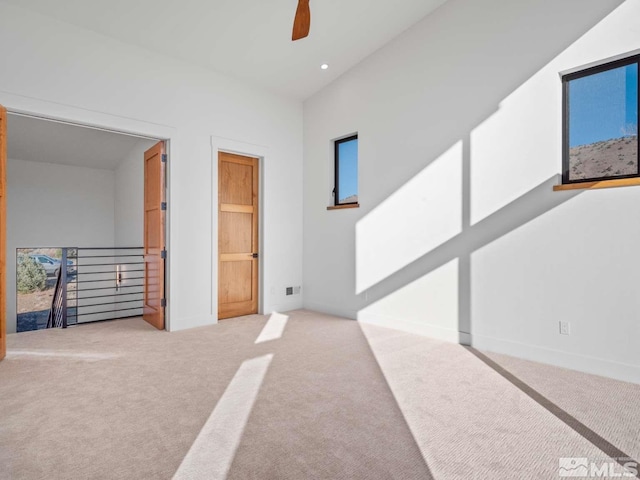 interior space featuring carpet, a towering ceiling, and ceiling fan