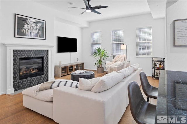 living room with a tiled fireplace, hardwood / wood-style floors, a healthy amount of sunlight, and ceiling fan