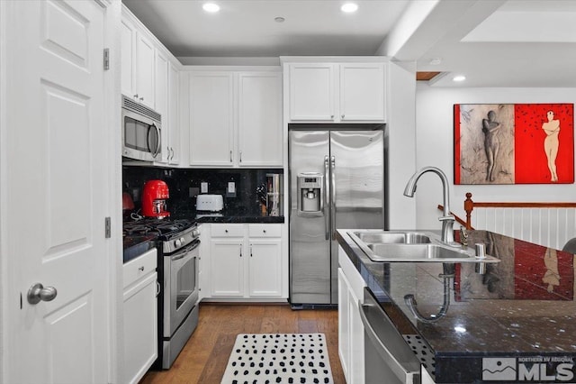 kitchen featuring sink, dark wood-type flooring, backsplash, stainless steel appliances, and white cabinets