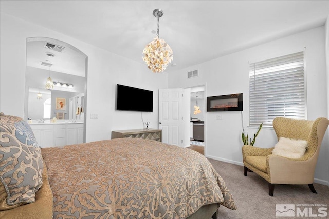 carpeted bedroom with a notable chandelier and ensuite bath