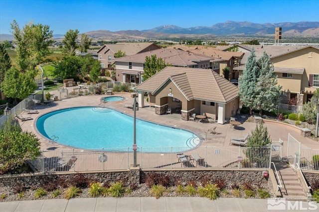 view of swimming pool featuring a hot tub, a mountain view, and a patio