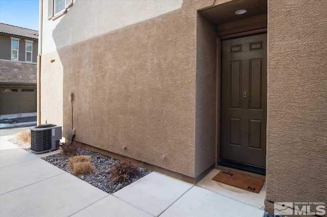 view of exterior entry featuring central air condition unit