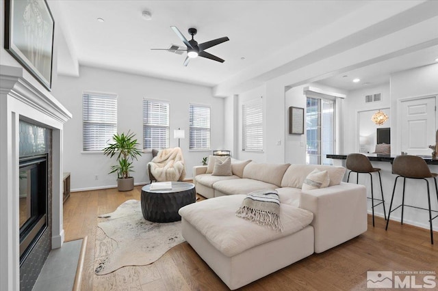 living room with ceiling fan, a fireplace, and light hardwood / wood-style floors