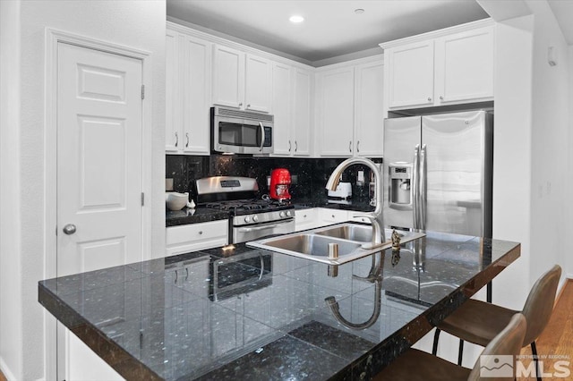 kitchen with sink, a kitchen breakfast bar, white cabinets, and appliances with stainless steel finishes