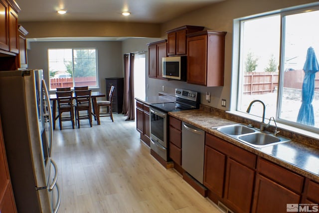 kitchen with stainless steel appliances, sink, and light hardwood / wood-style floors