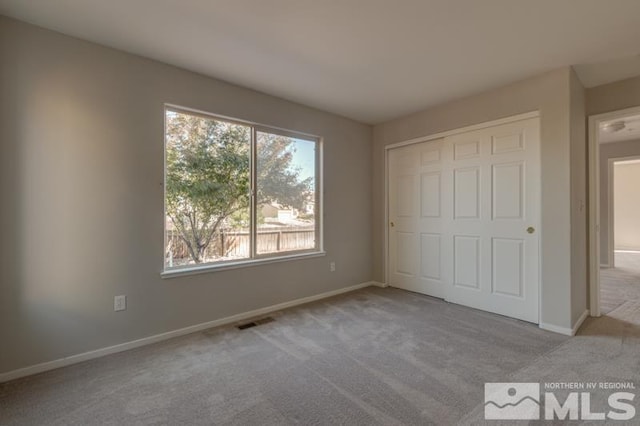 unfurnished bedroom featuring light colored carpet and a closet