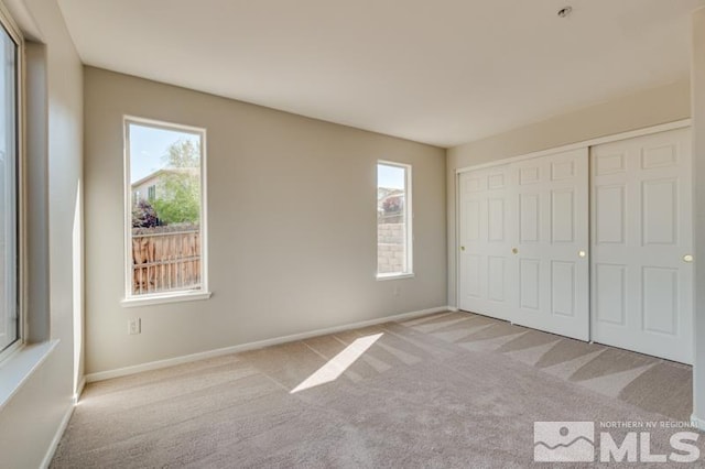 unfurnished bedroom featuring light colored carpet and a closet