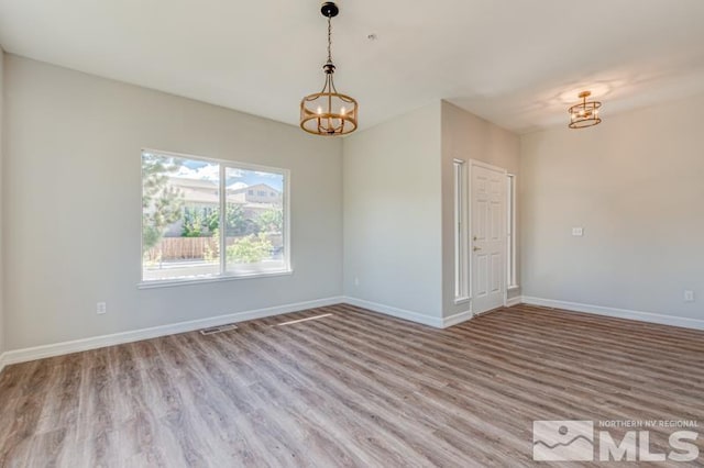 empty room featuring light hardwood / wood-style floors and a chandelier