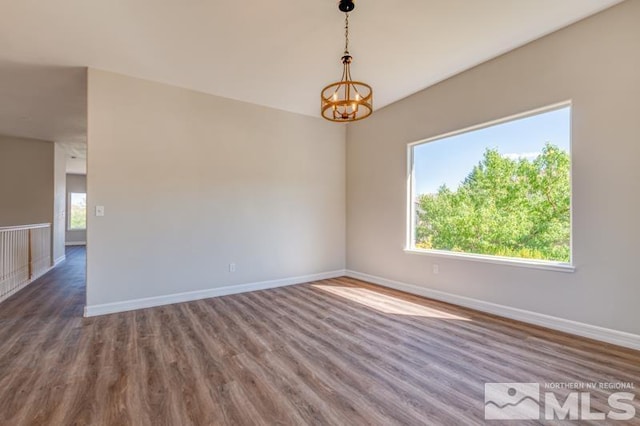 unfurnished room with dark hardwood / wood-style floors and a notable chandelier